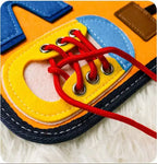 Chaussure éducative en feutrine colorée avec lacets rouges, jouet d'apprentissage pour enfants, développement de la motricité fine, sur tapis blanc.