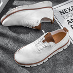 Chaussures de sport blanches pour hommes avec semelle épaisse, détails marron, sur fond gris. Style moderne et confortable, idéal pour la mode urbaine.