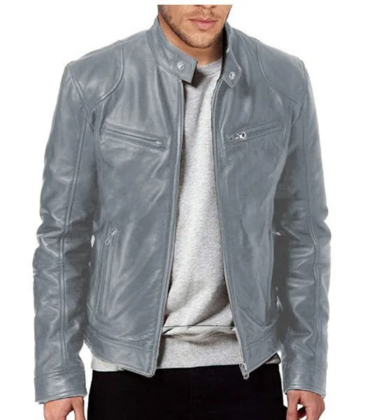 Homme portant un blouson en cuir gris, style motard, avec fermeture éclair et poches zippées, sur un pull gris clair. Mode masculine tendance.