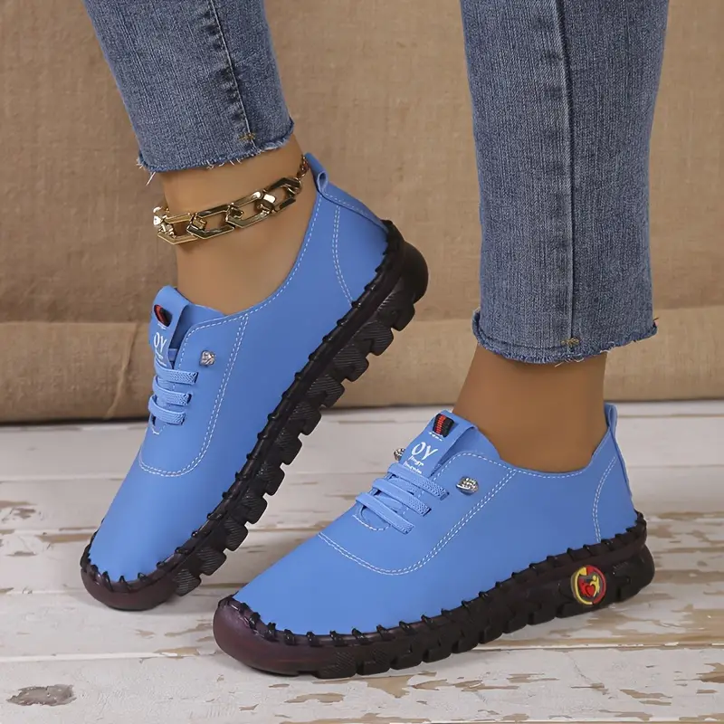 Chaussures de sport bleues pour femmes avec semelles noires, portées avec un jean. Design moderne et confortable, idéal pour la mode urbaine.
