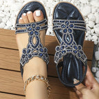 Sandales bleues ornées de strass, portées sur une terrasse en bois, avec un bracelet doré à la cheville. Mode estivale élégante et tendance.