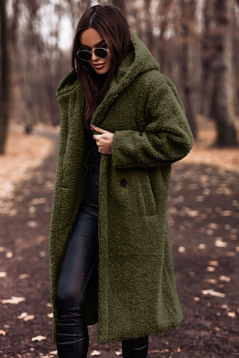 Femme en manteau vert en fausse fourrure, lunettes de soleil, marchant dans un parc automnal. Mode hiver, style chic, tendance vêtements chauds.