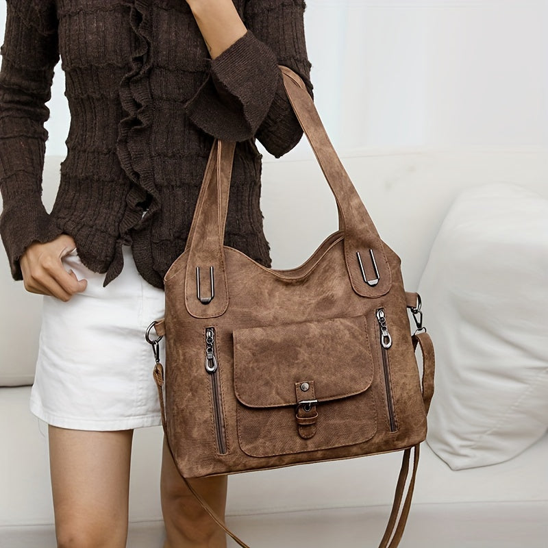 Sac à main en cuir marron porté par une femme en jupe blanche et pull marron. Design élégant avec poches zippées, idéal pour la mode féminine.