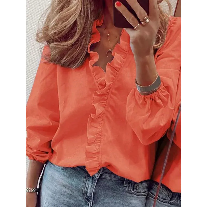 Femme portant une blouse orange à volants, manches longues, associée à un jean décontracté. Mode féminine, tenue élégante et tendance.