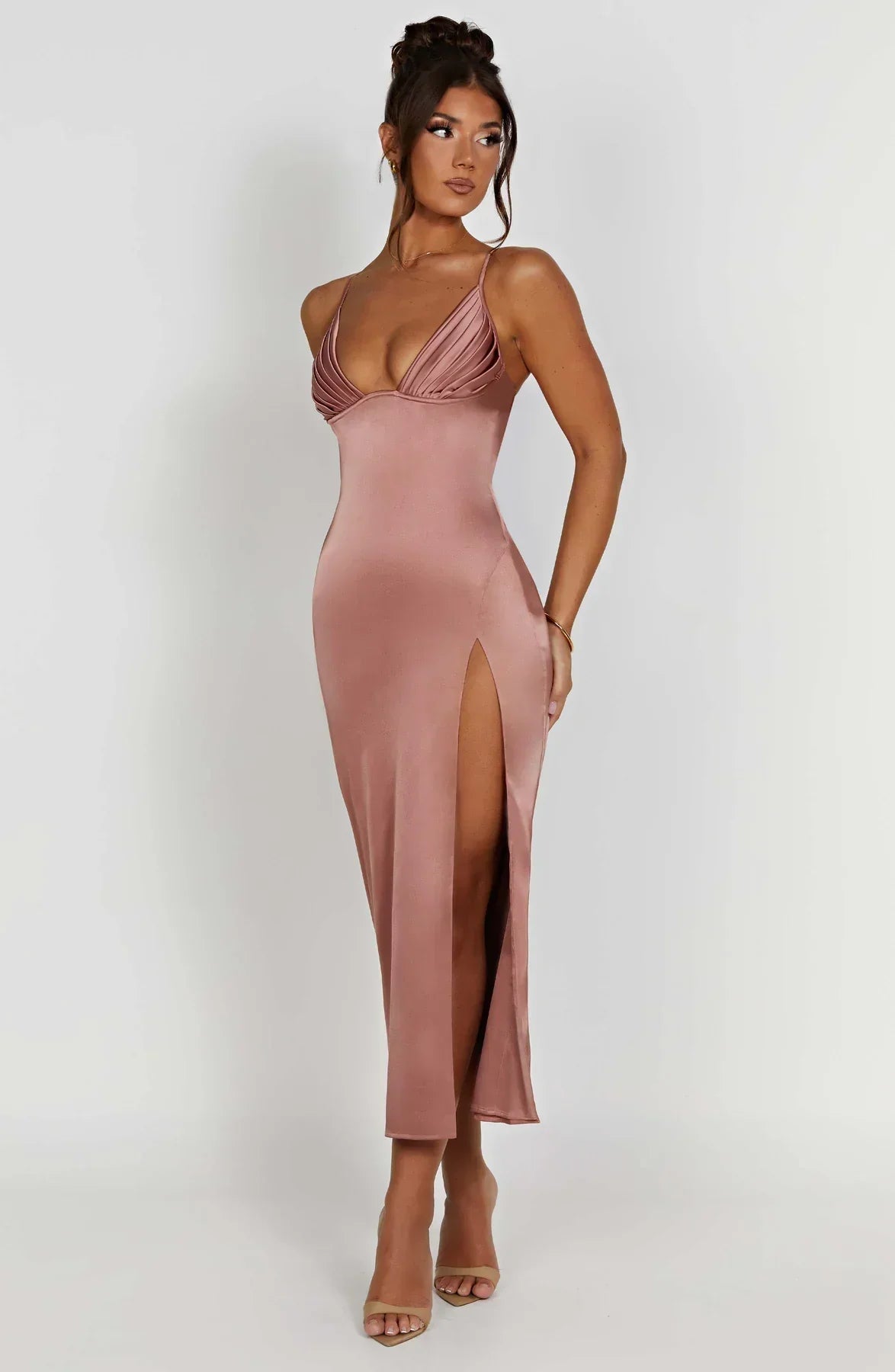 Robe longue satinée rose avec bretelles fines et fente haute, portée par une femme. Mode élégante, tenue de soirée chic, style glamour.