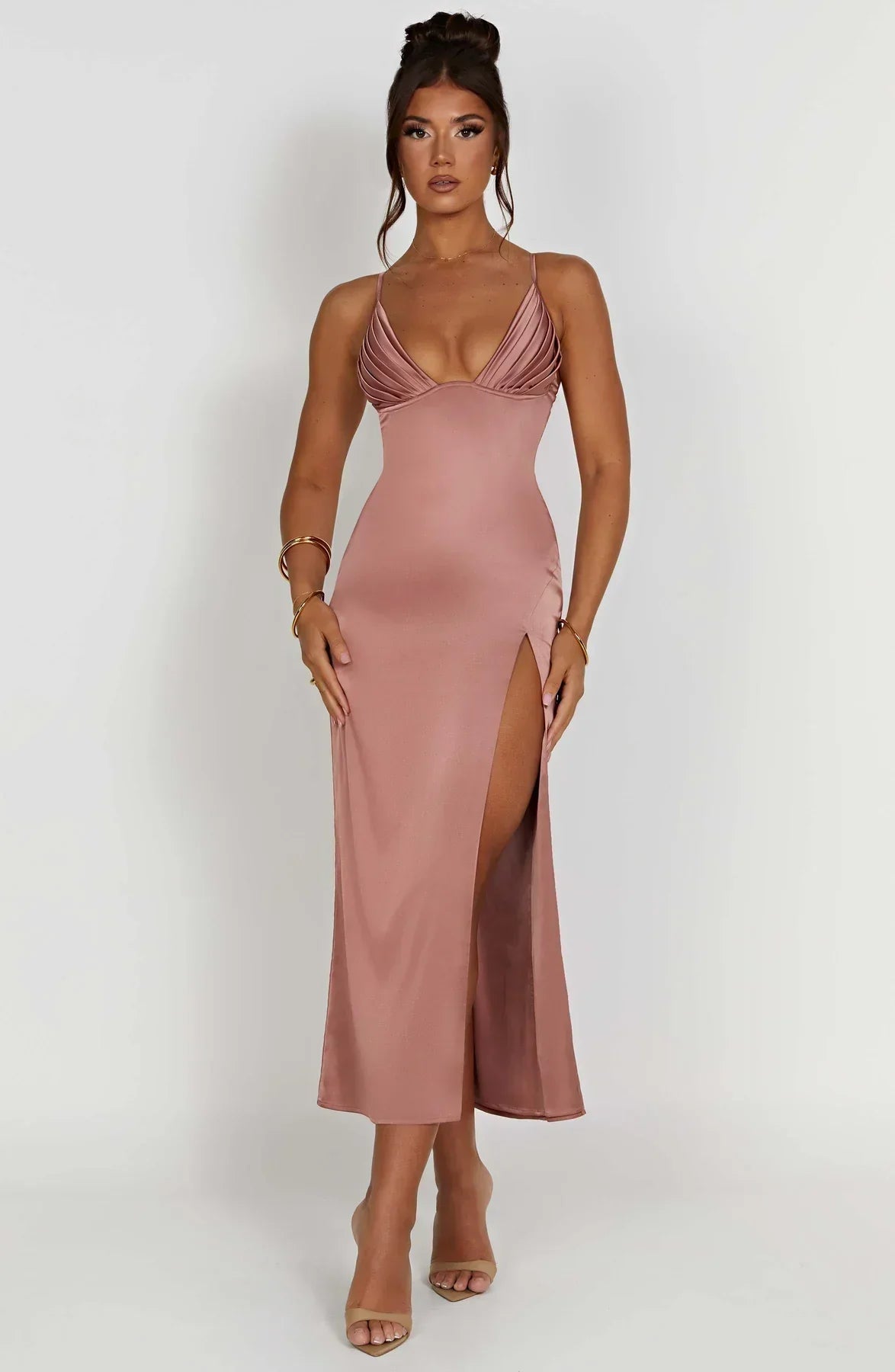 Robe longue rose satinée avec fente haute, décolleté plongeant, portée par une femme. Mode élégante, tenue de soirée chic, tendance 2023.