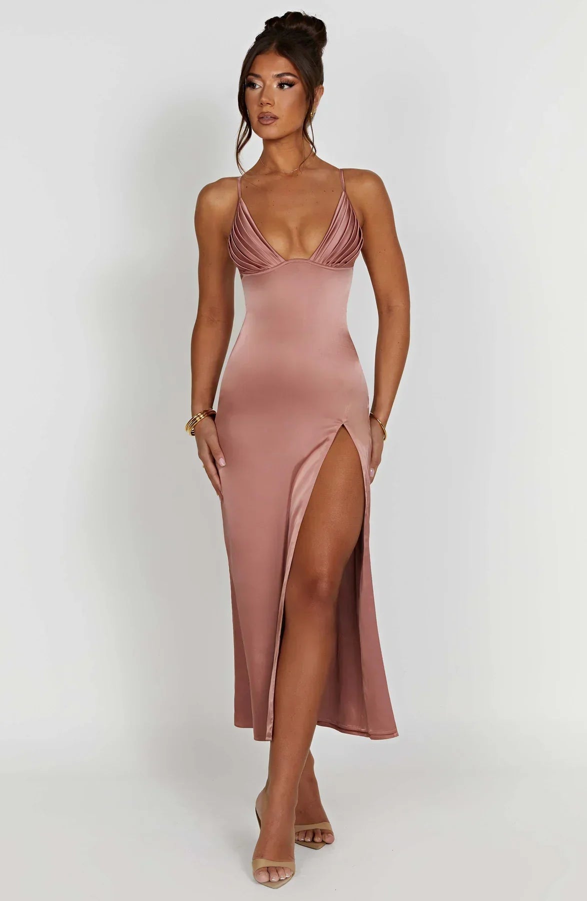 Robe longue satinée rose avec fente haute, décolleté plongeant, portée par une femme. Mode élégante, tenue de soirée chic, tendance 2023.