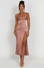 Robe longue satinée rose avec bretelles fines et fente haute, portée par une femme. Mode élégante, tenue de soirée chic, style glamour.