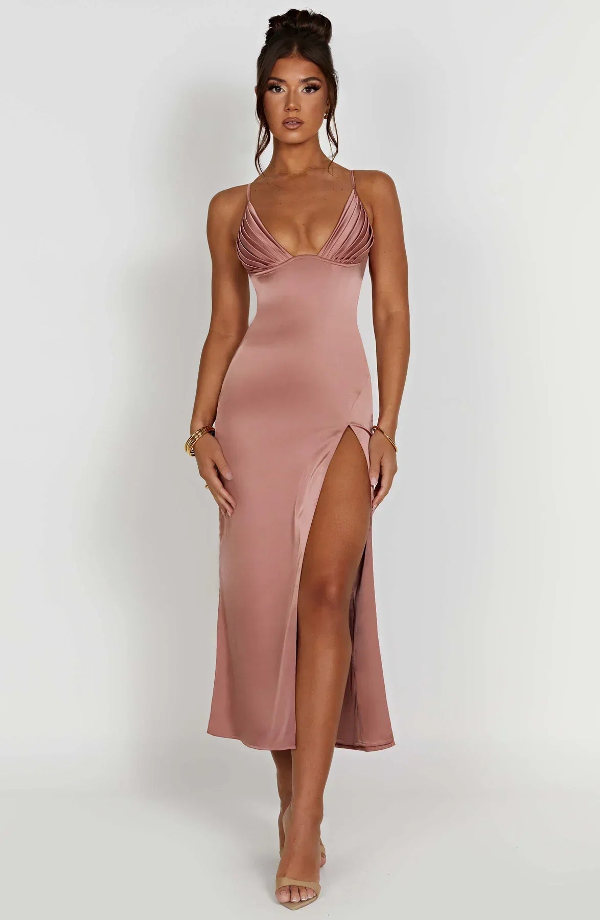 Robe longue satinée rose avec bretelles fines et fente haute, portée par une femme. Mode élégante, tenue de soirée chic, style glamour.