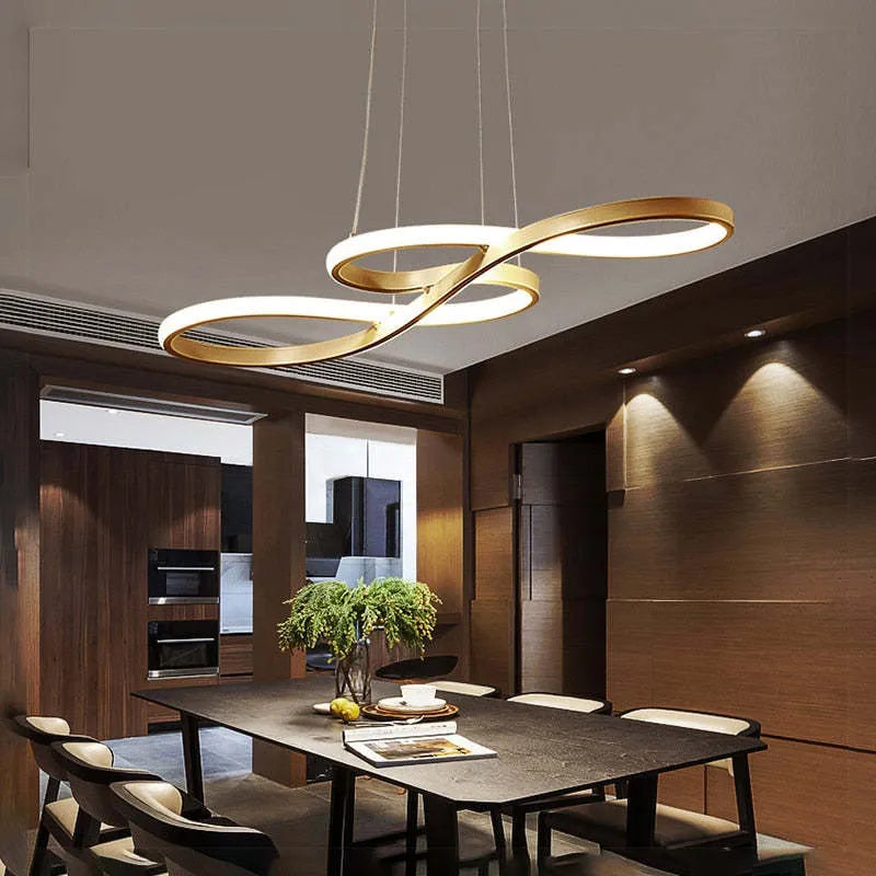 Suspension LED moderne dorée, design en forme de boucle, éclairant une salle à manger contemporaine avec table noire et chaises élégantes.