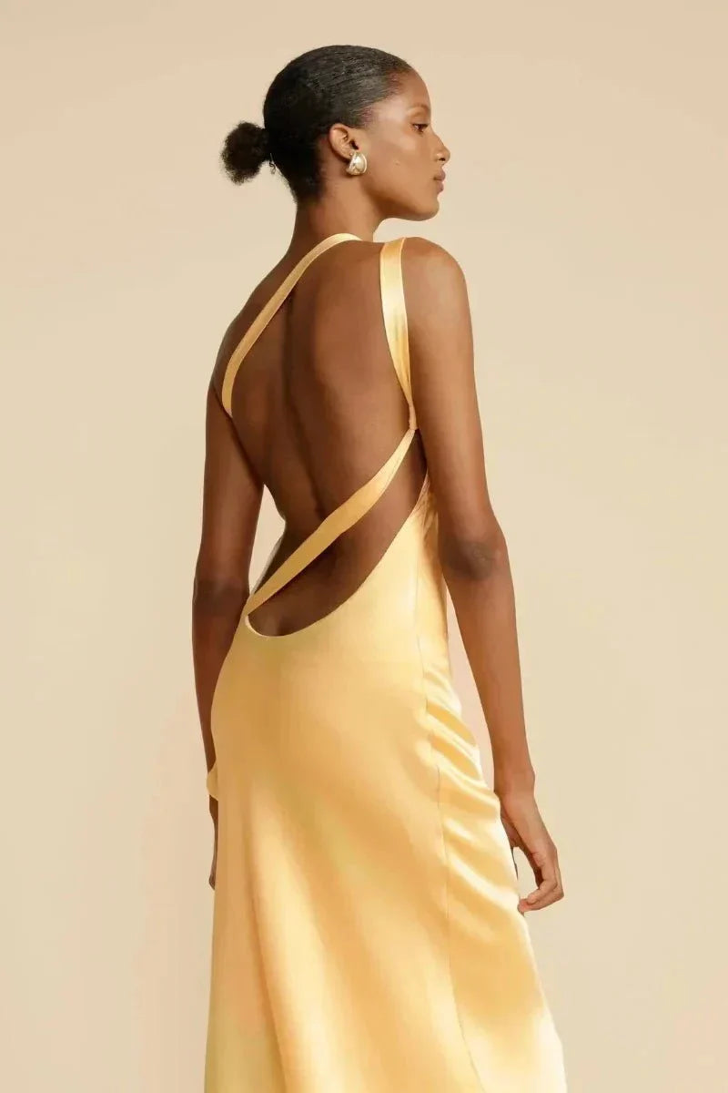 Femme en robe satinée jaune dos nu, élégante et moderne, posant sur fond beige. Mode féminine, style chic, tenue soirée.