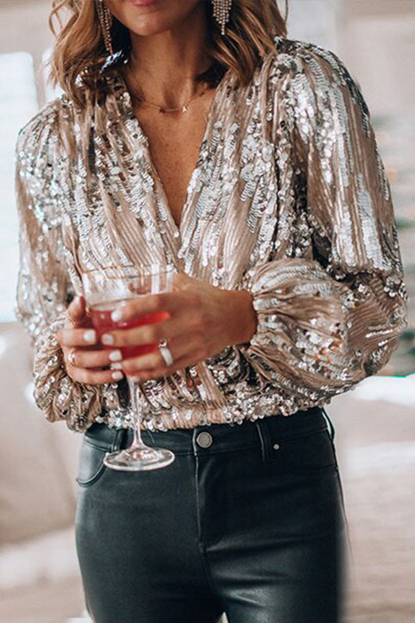 Femme portant un haut à paillettes argentées, tenant un verre de cocktail. Mode élégante, soirée chic, tenue glamour.
