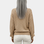 Femme aux cheveux gris portant un pull beige texturé et un pantalon blanc, vue de dos. Mode automne-hiver, style décontracté élégant.