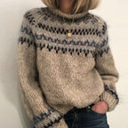 Femme portant un pull en laine tricoté à motifs nordiques, col roulé, tons beige et bleu, style hiver, mode cosy, tendance automne-hiver.