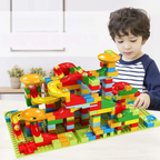 Enfant jouant avec un circuit de billes en blocs de construction colorés sur une table, jouet éducatif, développement créatif, intérieur lumineux.