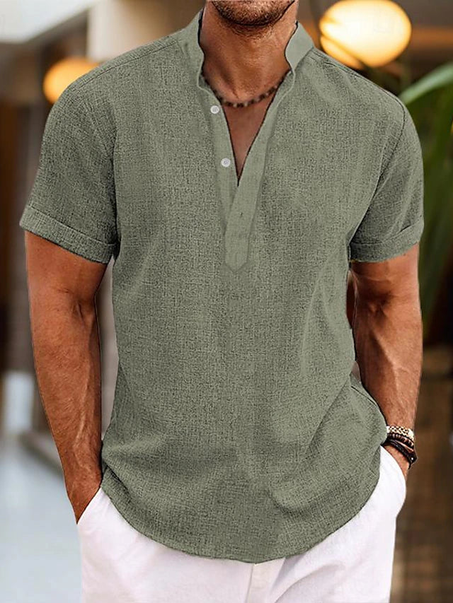 Homme portant une chemise en lin vert olive à col mao, manches courtes, avec un pantalon blanc. Mode estivale décontractée pour homme.