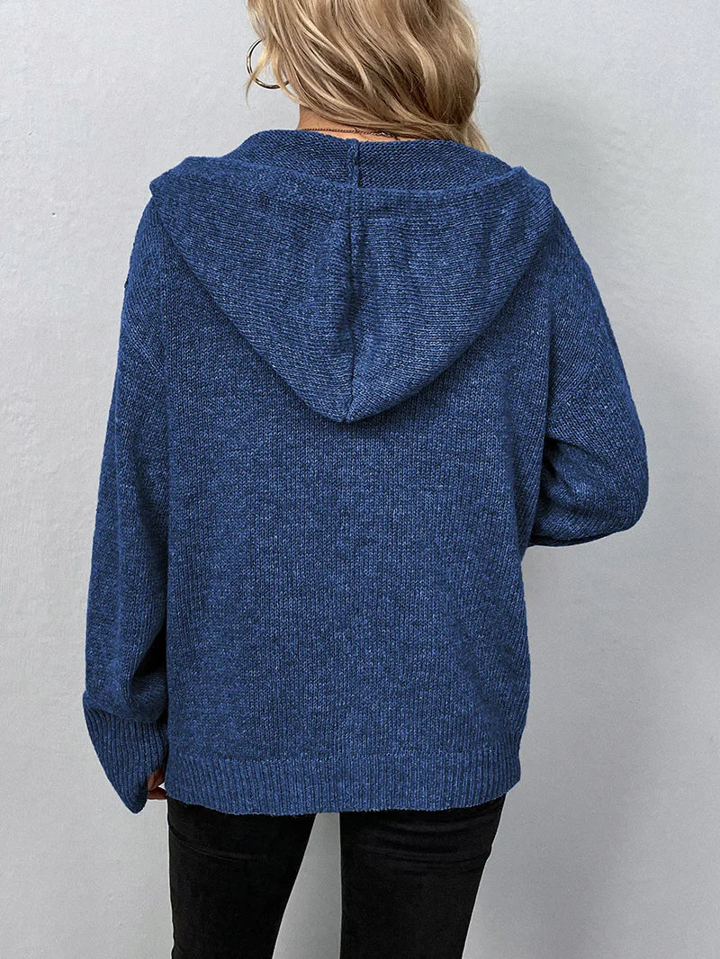 Femme portant un pull à capuche bleu en tricot, vue de dos. Mode automne-hiver, vêtement chaud et confortable, style décontracté.