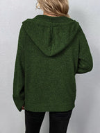 Femme portant un pull à capuche vert foncé en tricot, manches longues, dos visible. Mode automne-hiver, style décontracté et confortable.