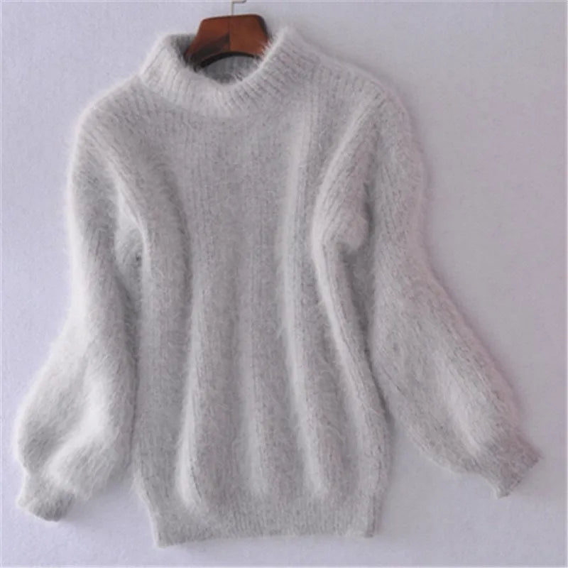 Pull en mohair gris clair sur cintre, manches longues bouffantes, col montant. Mode hiver, vêtement chaud et doux, tendance féminine.