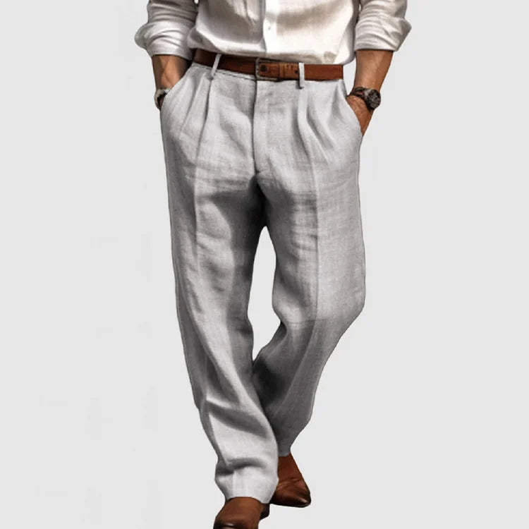 Homme portant un pantalon en lin gris clair, chemise blanche et ceinture marron, style élégant et décontracté, mode masculine moderne.