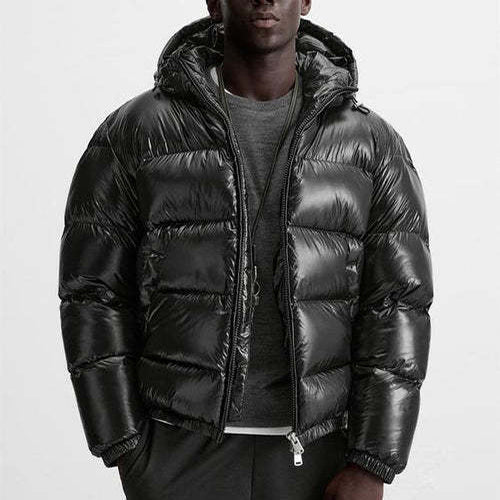 Homme portant une doudoune noire brillante avec capuche, style moderne et urbain, sur fond blanc. Mode hiver, veste chaude et tendance.