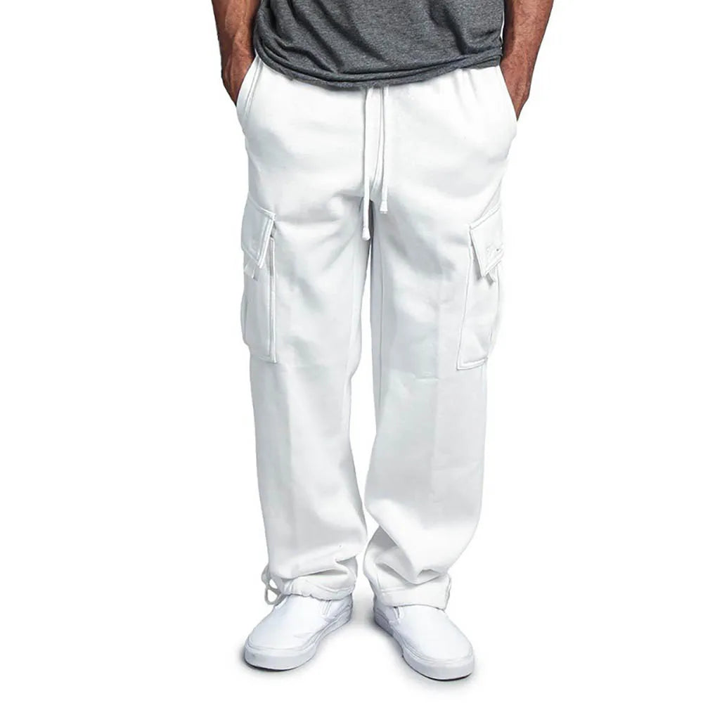 Pantalon cargo blanc pour homme avec poches latérales, cordon de serrage, porté avec des baskets blanches et un t-shirt gris. Mode décontractée.