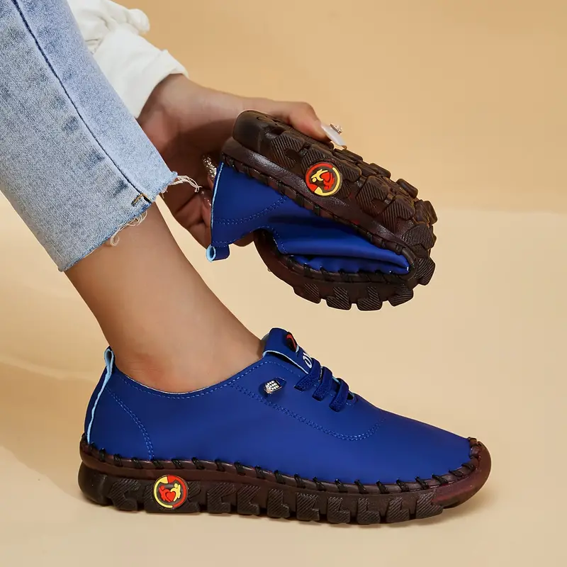 Chaussures décontractées bleues pour femmes avec semelles antidérapantes marron, design pliable, portées avec un jean clair, fond beige.