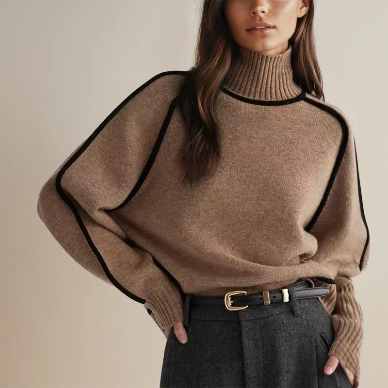 Femme portant un pull en laine marron à col roulé avec détails noirs, ceinture en cuir noir et pantalon gris. Mode automne-hiver élégante et chic.