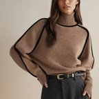 Femme portant un pull en laine marron à col roulé avec détails noirs, ceinture en cuir noir et pantalon gris. Mode automne-hiver élégante et chic.