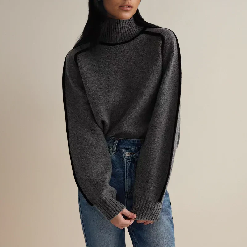 Femme portant un pull gris à col roulé et manches longues, associé à un jean bleu. Mode automne-hiver, style décontracté et élégant.