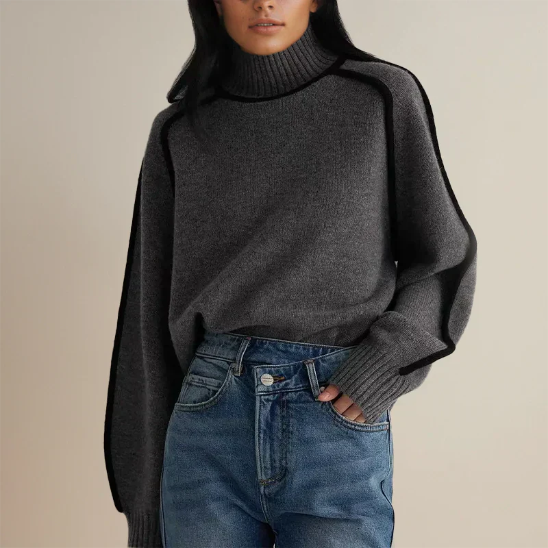 Femme portant un pull gris à col roulé avec des manches larges, associé à un jean bleu. Mode automne-hiver, style décontracté et élégant.