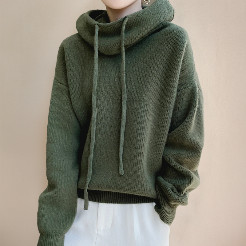 Pull-over vert à capuche en laine, manches longues, avec cordons, porté par une personne. Mode automne-hiver, style décontracté et confortable.