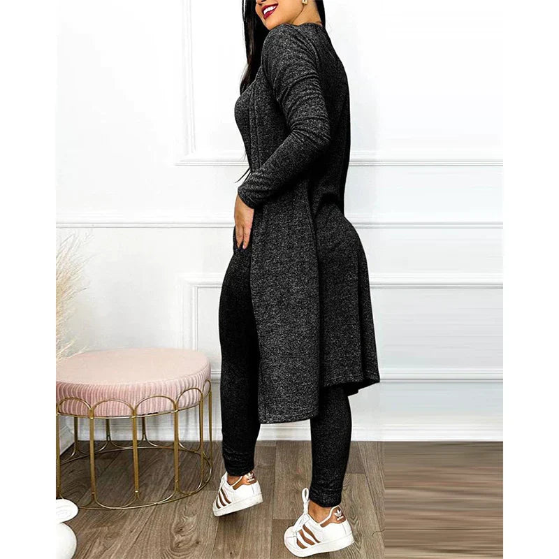 Femme portant un ensemble noir en tricot, tunique longue et leggings, posant dans un intérieur moderne. Mode féminine, tenue décontractée élégante.