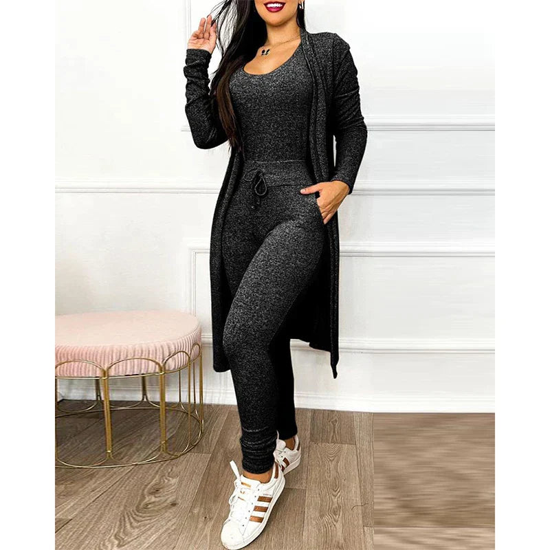 Femme en ensemble noir décontracté, cardigan long et pantalon ajusté, posant dans un intérieur moderne. Mode féminine, tenue confortable, style chic.