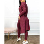 Femme portant un ensemble bordeaux élégant, composé d'une tunique longue et d'un legging, posant dans un intérieur moderne avec tabouret rose.