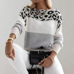 Femme portant un pull à motifs léopard noir et blanc, manches longues, assise avec un sac noir. Mode automne, style chic et décontracté.