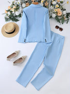 Costume bleu clair élégant pour femme, accompagné de chaussures beiges, chapeau de paille et lunettes de soleil, sur fond de fleurs blanches et jaunes.