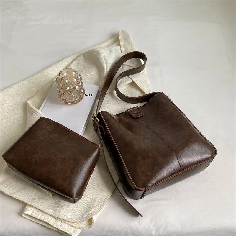 Sac à main en cuir marron avec pochette assortie sur fond blanc. Accessoire de mode élégant, tendance, idéal pour un look chic et sophistiqué.