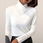Femme portant un pull blanc à col roulé, manches longues, associé à un pantalon noir. Mode élégante, tenue automne-hiver, style minimaliste.