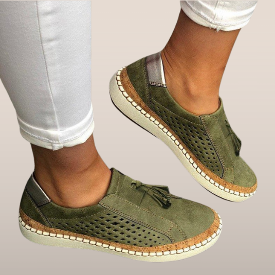 Chaussures décontractées vertes pour femmes, en cuir perforé, avec semelle en caoutchouc et détails en corde, portées avec un pantalon blanc.