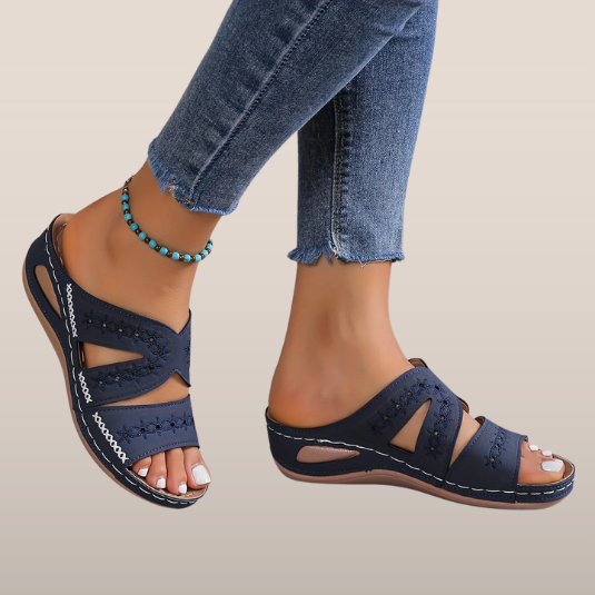 Sandales bleues en cuir avec motifs ajourés, portées avec un jean effiloché et un bracelet de cheville turquoise. Mode estivale, chaussures confortables.