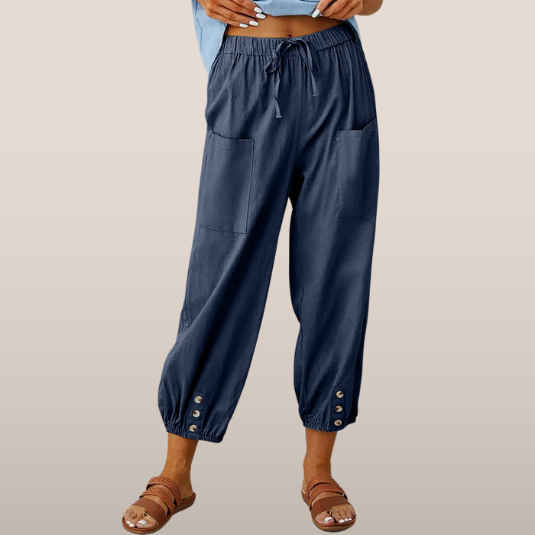 Pantalon ample bleu marine pour femme avec poches avant, taille élastique et boutons aux chevilles, idéal pour un style décontracté et confortable.