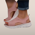 Sandales roses en maille respirante avec semelle blanche, portées par une personne en jean. Chaussures d'été confortables et tendance.