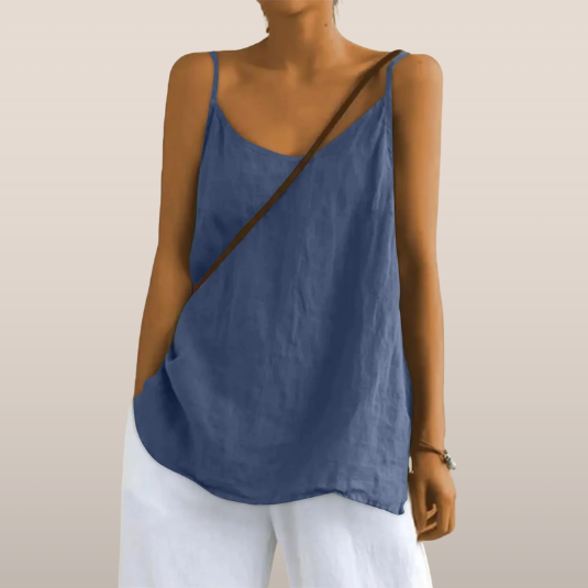 Femme portant un débardeur bleu en lin avec un sac en bandoulière marron, assorti à un pantalon blanc. Mode estivale décontractée et élégante.