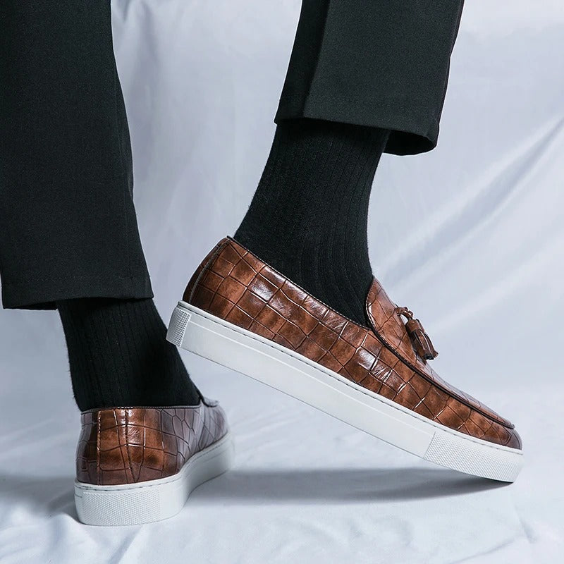 Chaussures mocassins en cuir marron à motif croco, semelle blanche, portées avec des chaussettes noires et un pantalon noir. Mode élégante masculine.