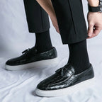 Chaussures mocassins en cuir noir texturé avec semelle blanche, portées avec des chaussettes noires et un pantalon noir. Style élégant et moderne.