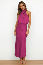 Robe longue fuchsia élégante avec col drapé, portée par une femme sur fond blanc. Mode féminine chic, tenue de soirée tendance.