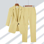 Costume femme élégant beige clair, veste à un bouton et pantalon ajusté, suspendu sur cintres, mode professionnelle, tenue de bureau chic.