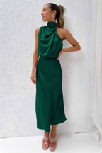 Robe longue verte élégante, sans manches, col haut drapé, portée par une femme. Mode féminine chic, tenue de soirée tendance.