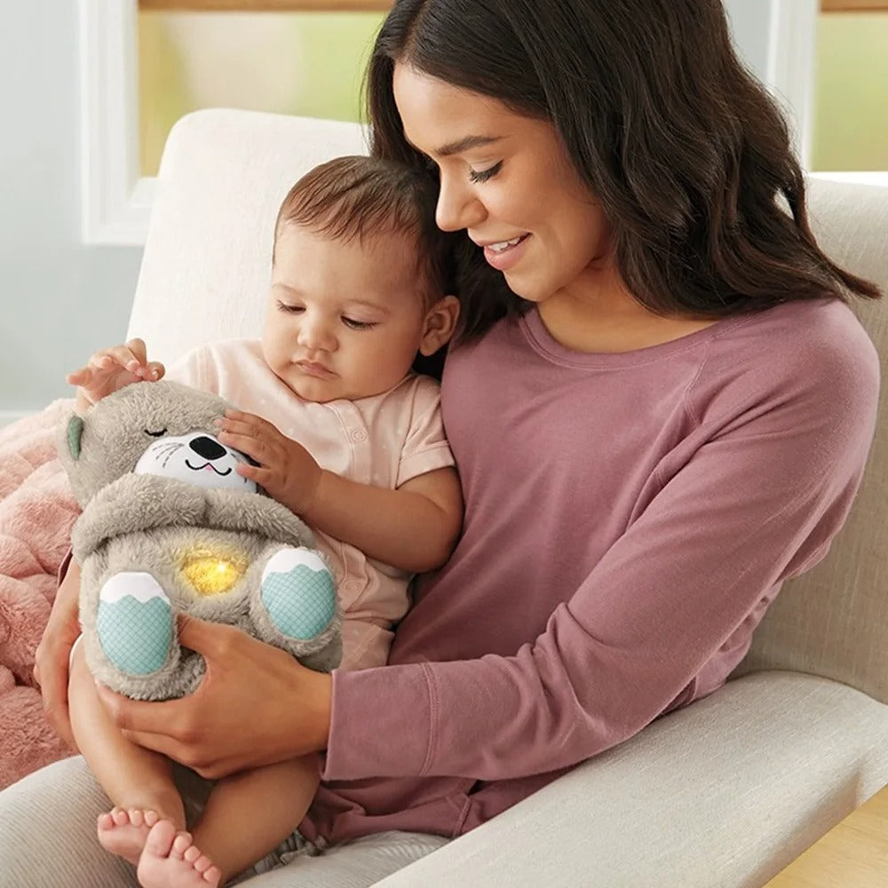Maman souriante tenant un bébé avec une peluche loutre lumineuse. Jouet interactif pour bébé, cadeau naissance, moment câlin.